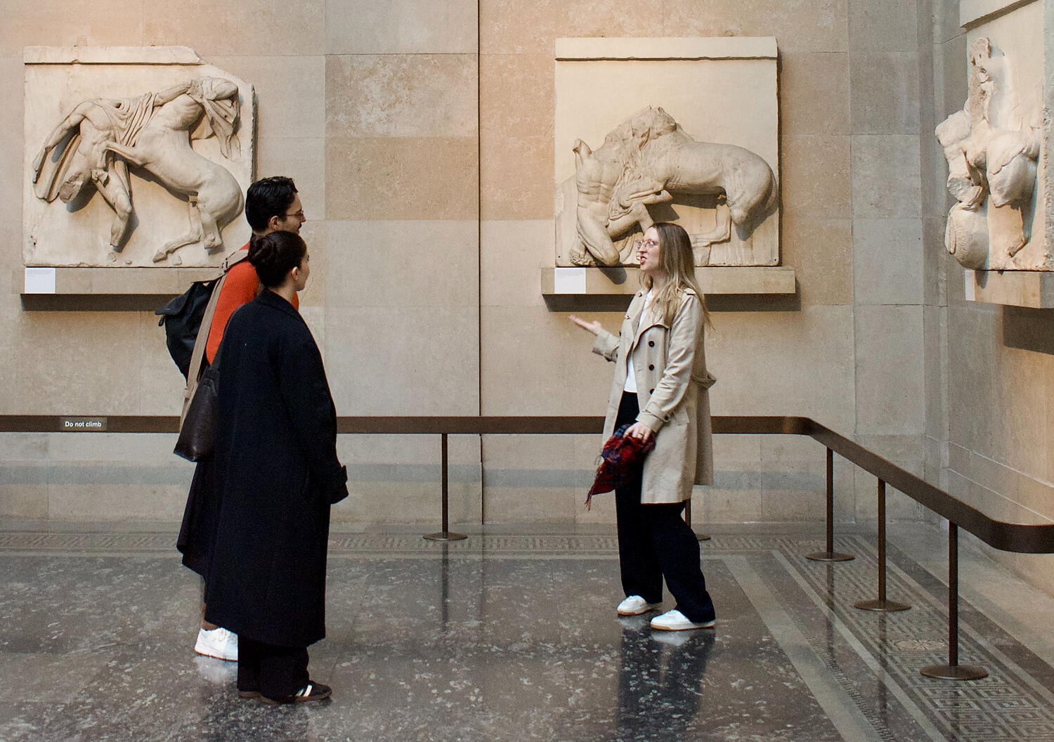 A photograph of a tour guide showing visitors around the British Museum, specifically around the Parthenon marbles, also known as Elgin marbles.